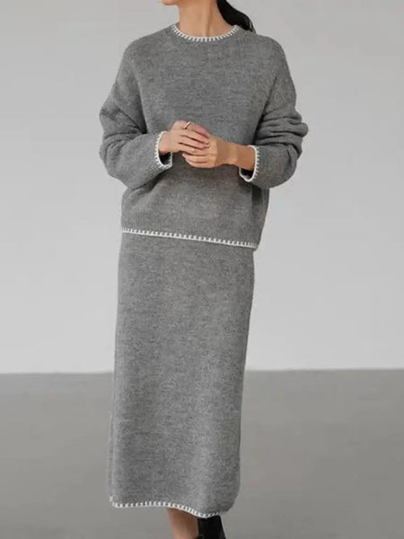 Person wearing a gray sweater and skirt set against a plain background