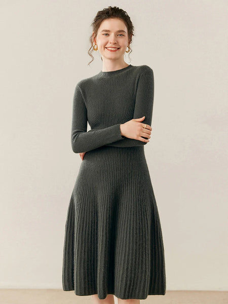 Woman wearing a dark green ribbed dress against a plain background