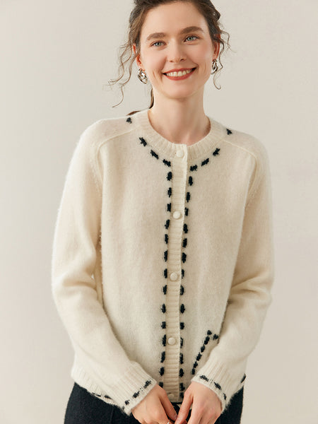 Woman wearing a cream cardigan with black details on a plain background