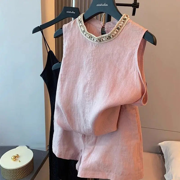 Pink sleeveless top & shorts set with embellished neckline on a hanger against a neutral background
