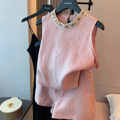Pink sleeveless top & shorts set with embellished neckline on a hanger against a neutral background