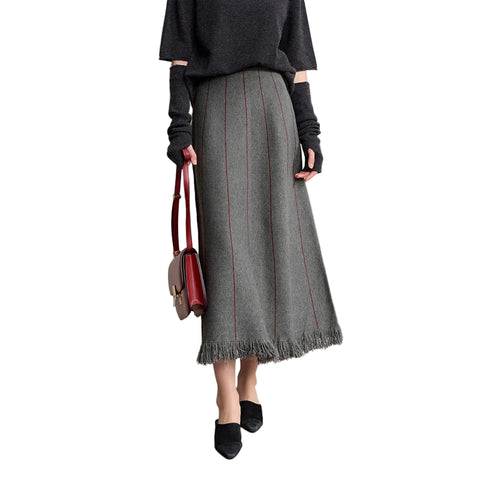 Person wearing a gray sweater and skirt with a red handbag on a plain background, featuring the brand 'Amii'.