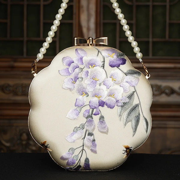 Handbag with floral design and pearl handle on a dark background