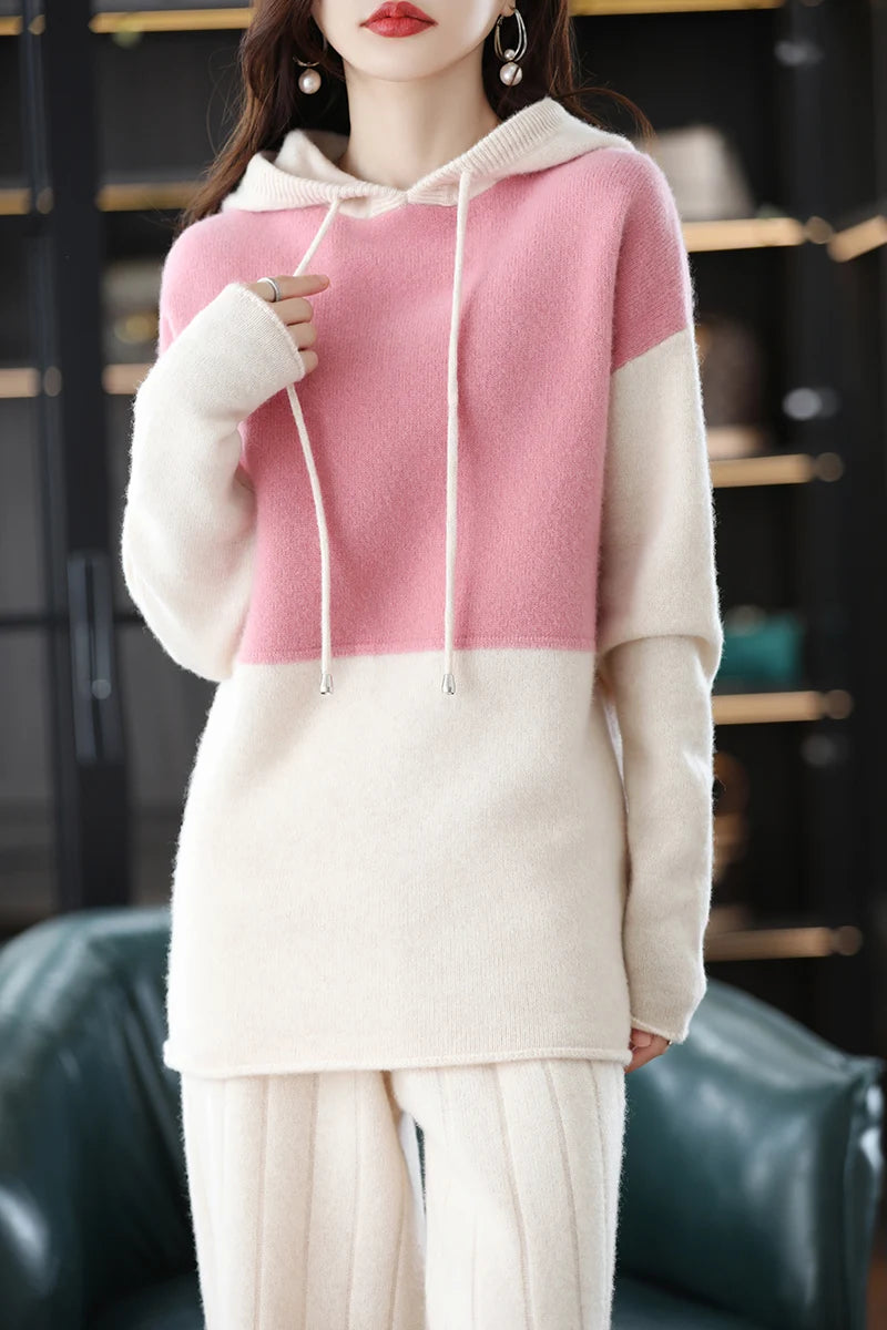 Person wearing a pink and white two-tone hoodie with a blurred background