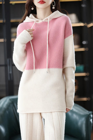 Person wearing a pink and white two-tone hoodie with a blurred background