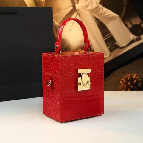 Red textured handbag with a gold clasp on a white surface.