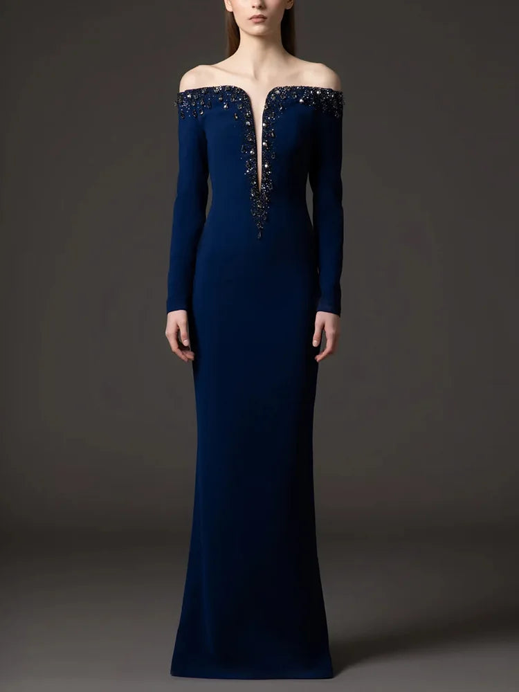 Navy blue off-shoulder gown with intricate detailing on a dark background