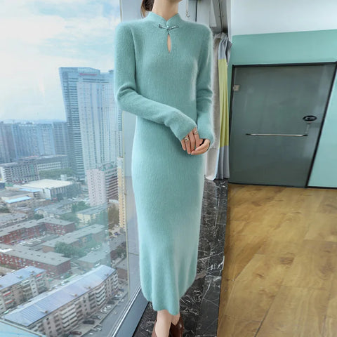 Person wearing a light blue dress standing in a room with a cityscape view.