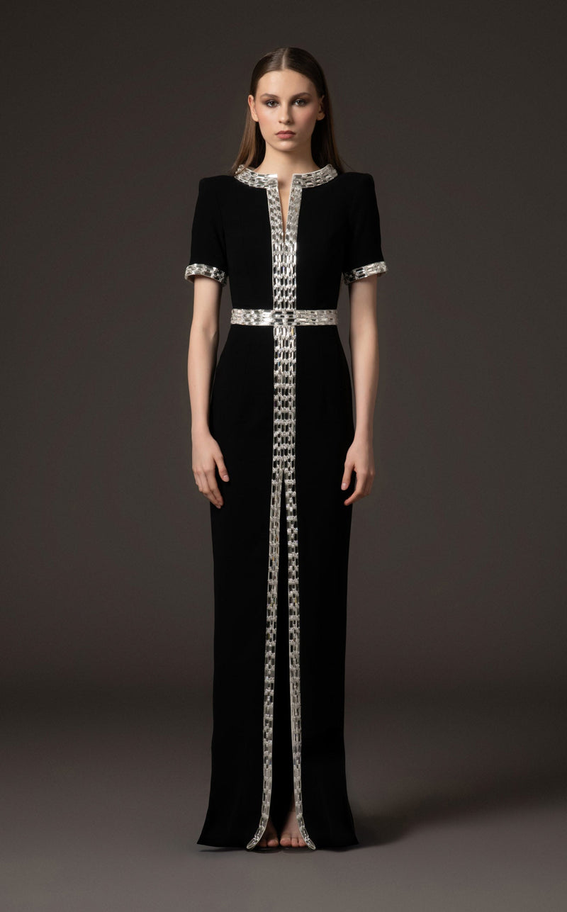 Black evening gown with silver embellishments on a model against a dark background