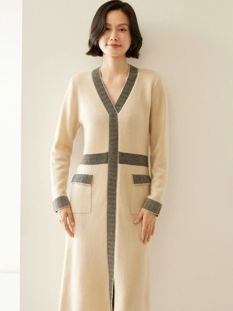 Woman wearing a long beige cardigan with gray accents against a plain background