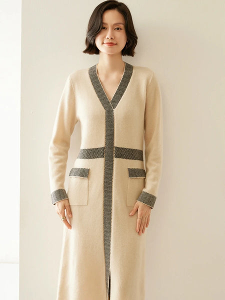 Woman wearing a long beige cardigan with gray accents against a plain background