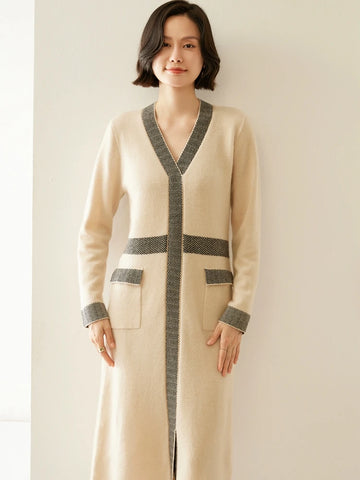 Woman wearing a long beige cardigan with gray accents against a plain background