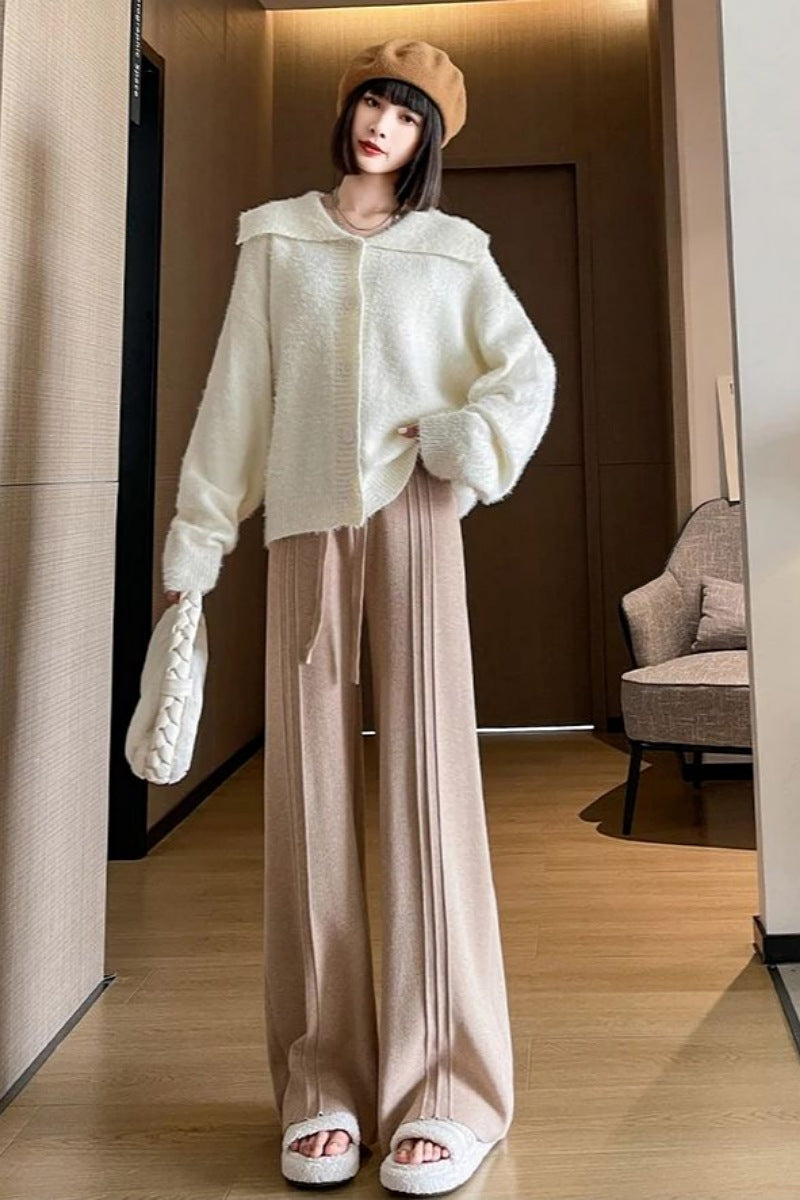 Woman wearing a cream sweater and beige pants in an indoor setting