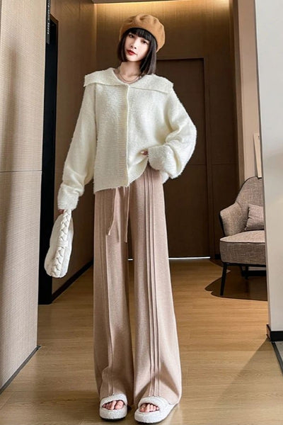 Woman wearing a cream sweater and beige pants in an indoor setting
